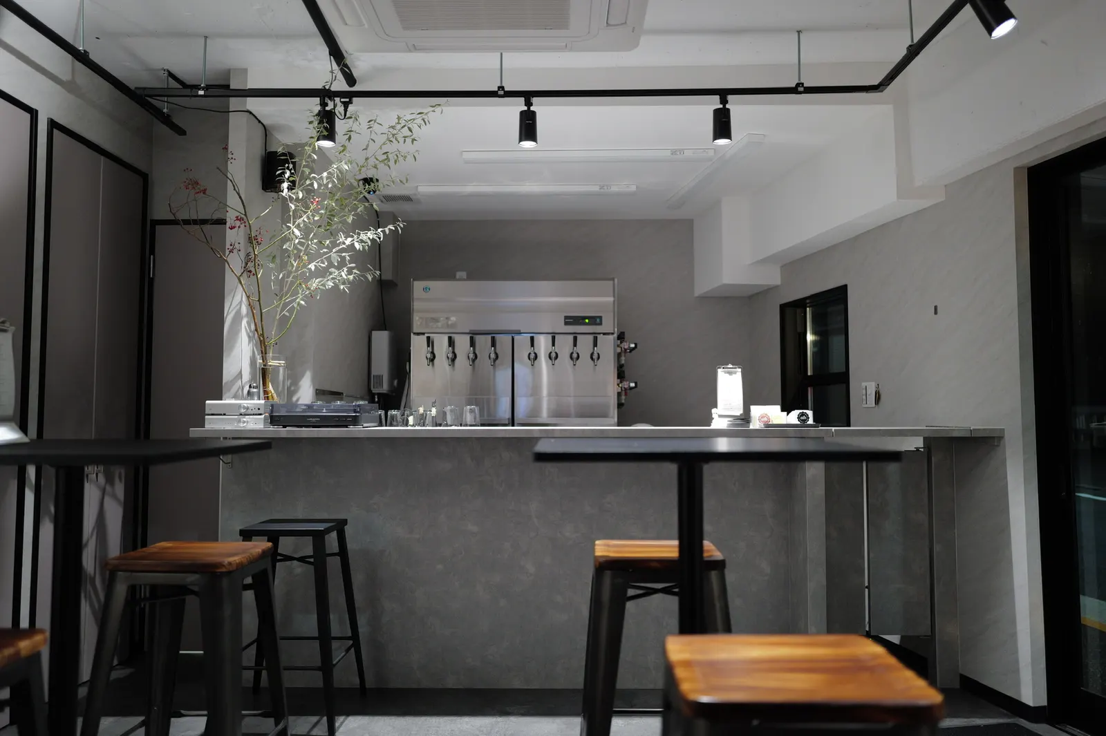 The Athipatai taproom bar: an eight-tap stainless steel dispenser, a turntable and hi-fi on the counter, and high tables with wooden stools under track lighting.